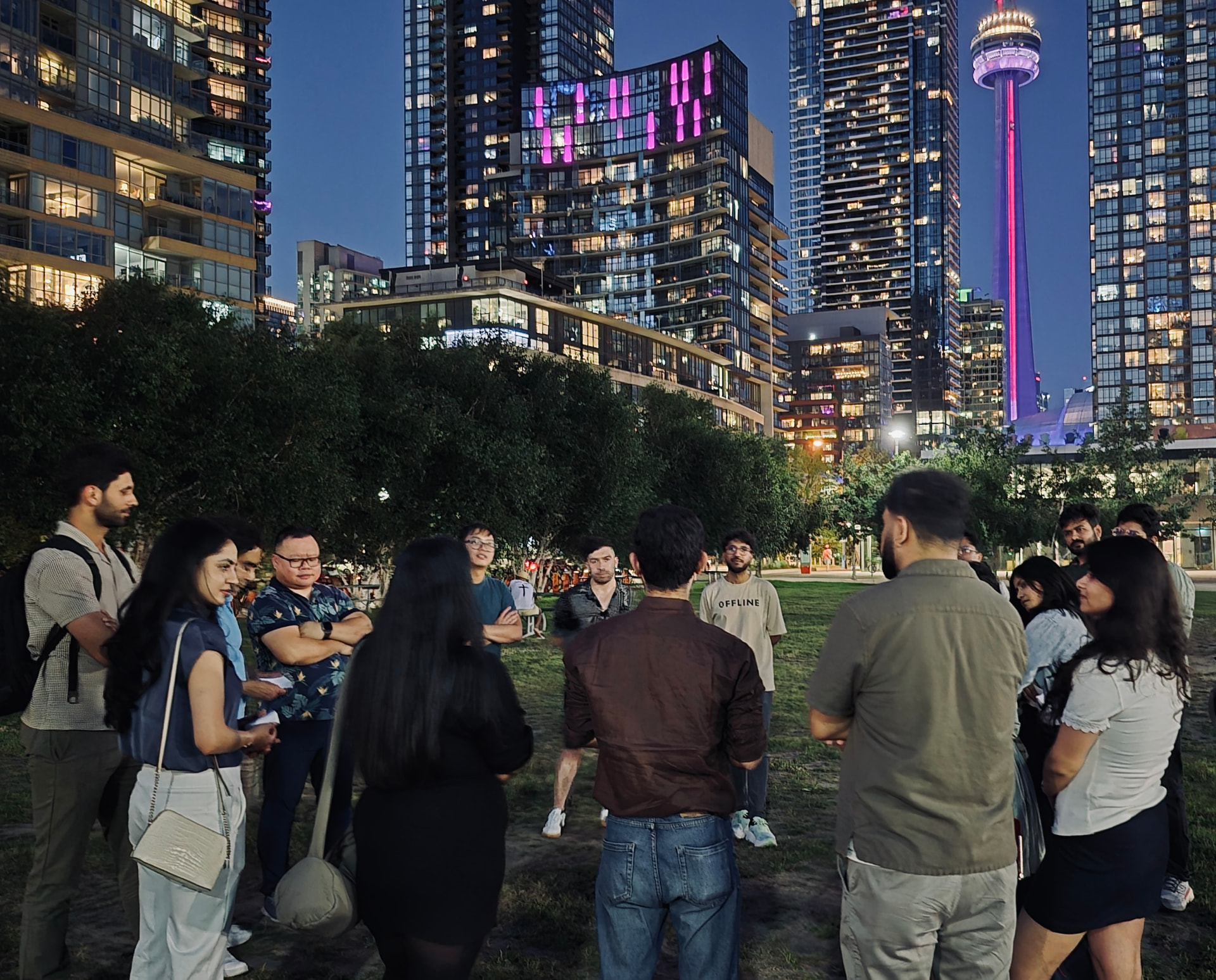 A group in a circle on a field with the Toronto skyline behind them