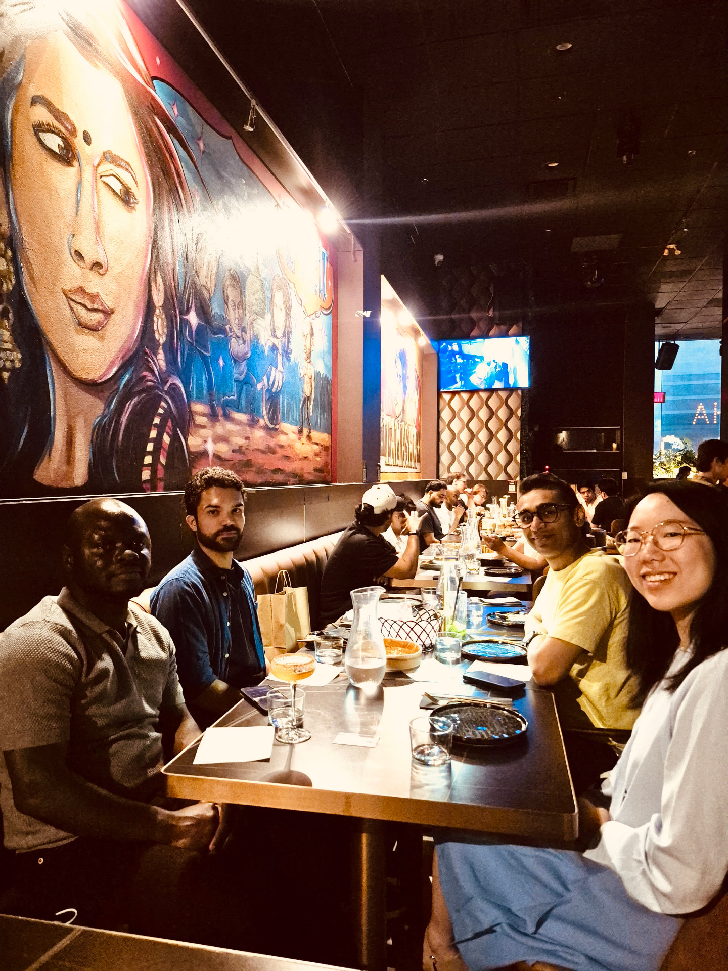 Four people looking at the camera at the end of a long table